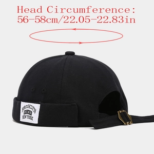 Detail of adjustable strap and brass buckle on a black cotton canvas brimless cap
