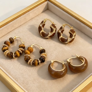 Macro detail of vintage gold-plated hoop earrings set with faux tiger eye stones