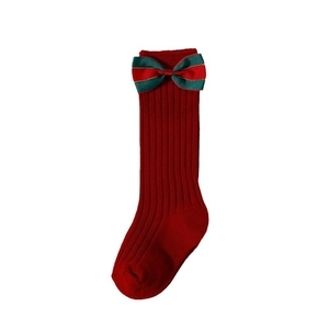 Festive red Christmas socks for toddlers with green ribbon bow accents on white background
