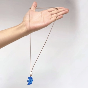 Detailed macro view of a bohemian blue bird resin pendant with brown braided cord