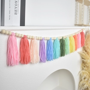 Detail of colorful rainbow cotton tassels and natural wood beads on a boho wall garland