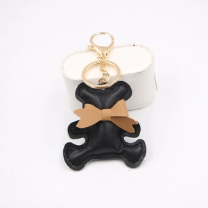 Cute black PU leather bear keychain with brown bow and gold metal ring on white background