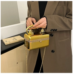 Detail of gold mirror acrylic clutch bag featuring exquisite lion head handles and chain