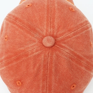 Hochauflösendes Detail der Oberseite einer verwaschenen Baumwoll-Baseballkappe in Orange