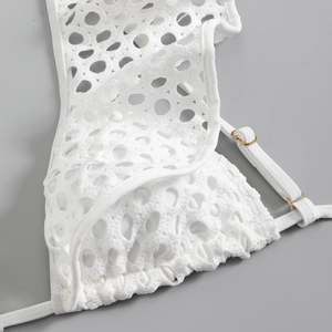 Detail of white crochet swimsuit featuring delicate mesh texture and gold metal hardware