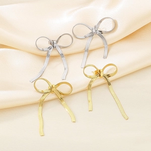 Elegant 18K gold and silver stainless steel bow knot stud earrings on yellow silk fabric