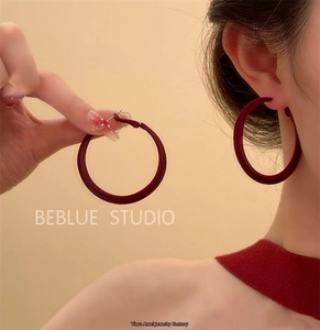 Close-up of burgundy red velvet texture large hoop earrings with minimalist metal posts