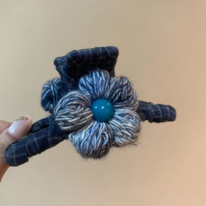 Detail of blue plaid fabric hair claw clip with a hand-knitted flower and turquoise bead