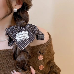 Detailed close-up of brown checkered fabric scrunchie with cute bear print and text detail