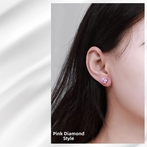 Close-up of pink moissanite stud earring with four-claw silver setting on model ear