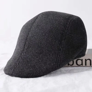 Detailed side view of dark grey herringbone wool flat cap for men with warm fabric texture