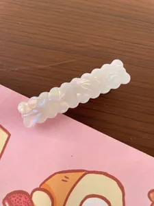 Detail of a pearlescent white rectangular wave hair clip with a shimmering mother-of-pearl finish