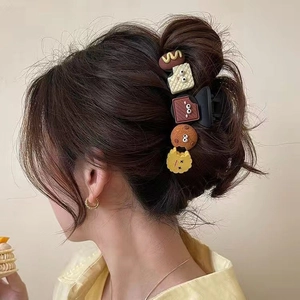 Braune Haarklammer mit süßen Keks- und Schokoladenanhängern in einer eleganten Hochsteckfrisur