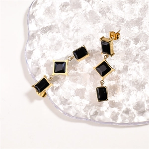 Detailed macro view of long drop earrings with square black stones in gold setting