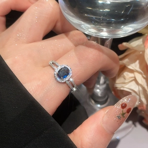 Detailed view of silver ring with large oval blue gemstone and micro-pave zircon crystals