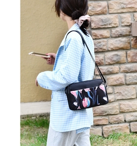 Outdoor model shot of black oxford floral crossbody bag with multiple zip pockets