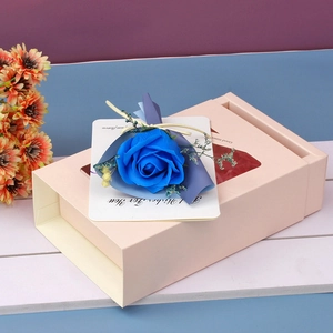 Detail of blue soap rose bouquet on beige drawer gift box with best wishes greeting card