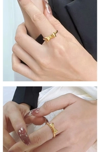 Detailed view of elegant gold bow ring featuring a polished finish on model's finger