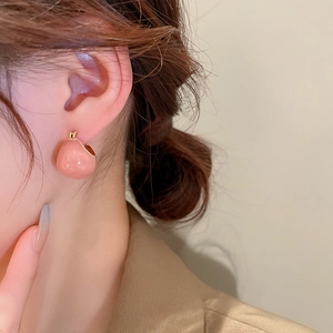 Close-up of pink sphere stud earrings worn by a model for a stylish casual look