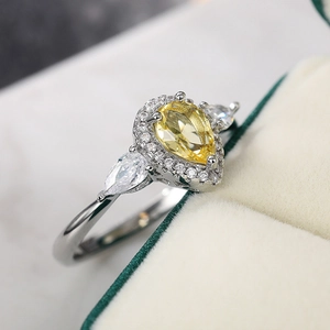 Macro shot of yellow pear cut stone with halo setting on a silver ring band