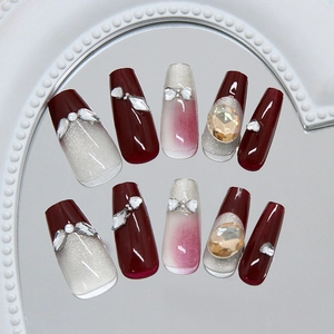 Cat eye wine red press-on nails with silver glitter and rhinestone bow decoration