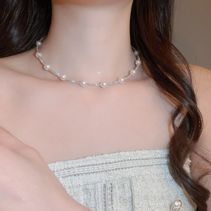 Elegant pearl and rhinestone necklace set worn by a model in a tweed jacket close-up