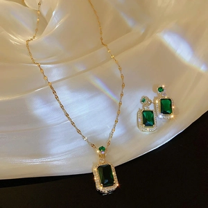 Macro detail of luxury gold jewelry set with emerald green stones on white silk