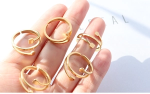 Detailed view of five adjustable 18K gold plated titanium rings set in geometric style