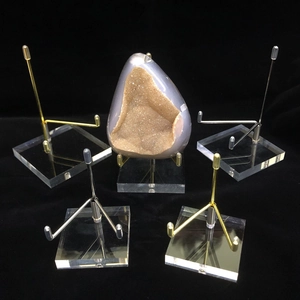 Macro shot of clear acrylic display stands with gold and silver metal arms on black background