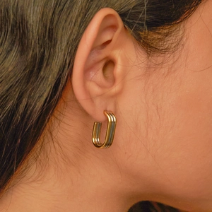 Close-up of three-tone rectangle hoop earrings in gold, silver and rose gold on ear