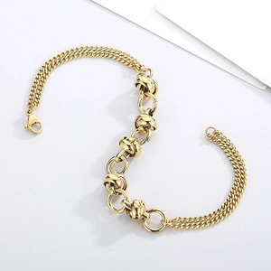 Detail of a layered golden stainless steel chain bracelet with interlocking knot rings