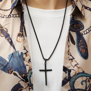 Close-up of a black stainless steel cross pendant necklace worn on a printed shirt