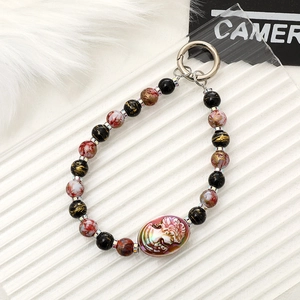 Detailed view of a vintage beaded phone charm with lady relief pendant and silver metal clasp