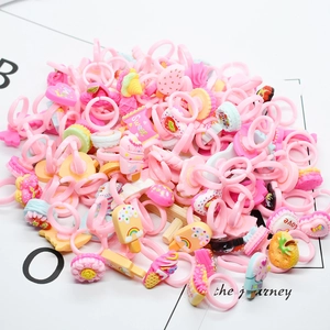 Detail of pink plastic toy rings for girls with miniature 3D dessert and candy decorations