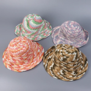 Detail view of colorful hand-woven straw sun hats in four vibrant mixed color patterns