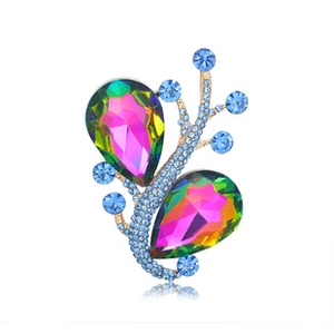 Detail of a gold butterfly brooch with gradient teardrop crystals and blue rhinestones