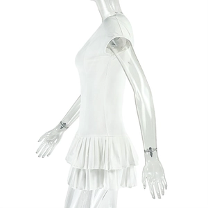 Detail of white mini dress featuring double-layered pleated ruffle hem and slim fit cut