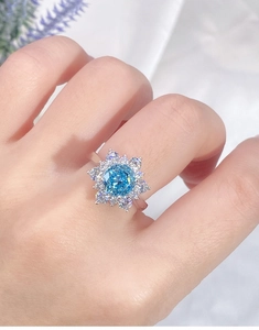 Detail of a sparkling sky blue round gemstone ring with snowflake halo on a model's hand