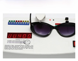 Detail view of oval sunglasses on UV400 tester showing gradient purple lens protection
