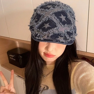 Detail of blue denim beret featuring star embroidery and distressed frayed edge finish