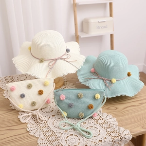 Detail of straw hat and bag set with colorful plush pom-poms and wavy brim for kids