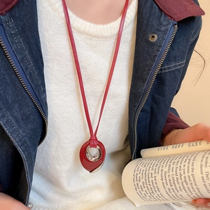 Detailed view of red drop pendant necklace with silver accents on leather cord