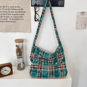 Détail d'un sac bandoulière en toile à carreaux verts avec boutons vintage et texture