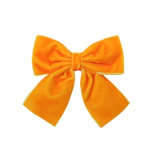 Detailed view of a bright orange velvet hair bow clip with soft texture on white background