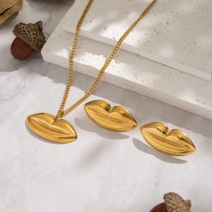 Golden lip necklace and earrings set on marble surface with minimalist aesthetic props