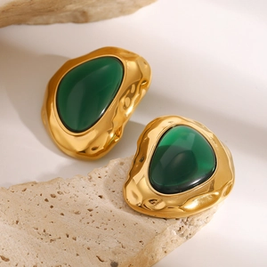 Macro detail of vintage gold irregular metal earrings with translucent dark green resin