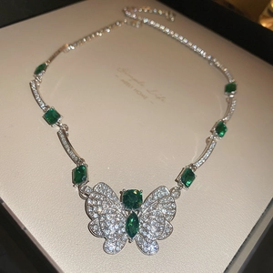 Macro view of vintage silver butterfly necklace with green zircon gems on a display board