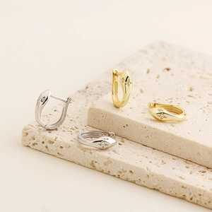 Close-up of minimalist gold and silver snake hoop earrings with sparkling zirconia stones