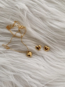 Detail of gold heart pendant necklace and stud earrings set with sparkling crystals