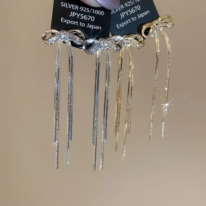 Nahaufnahme eleganter Zirkon-Schleifenohrringe mit langen Schlangenkette-Quasten in Gold